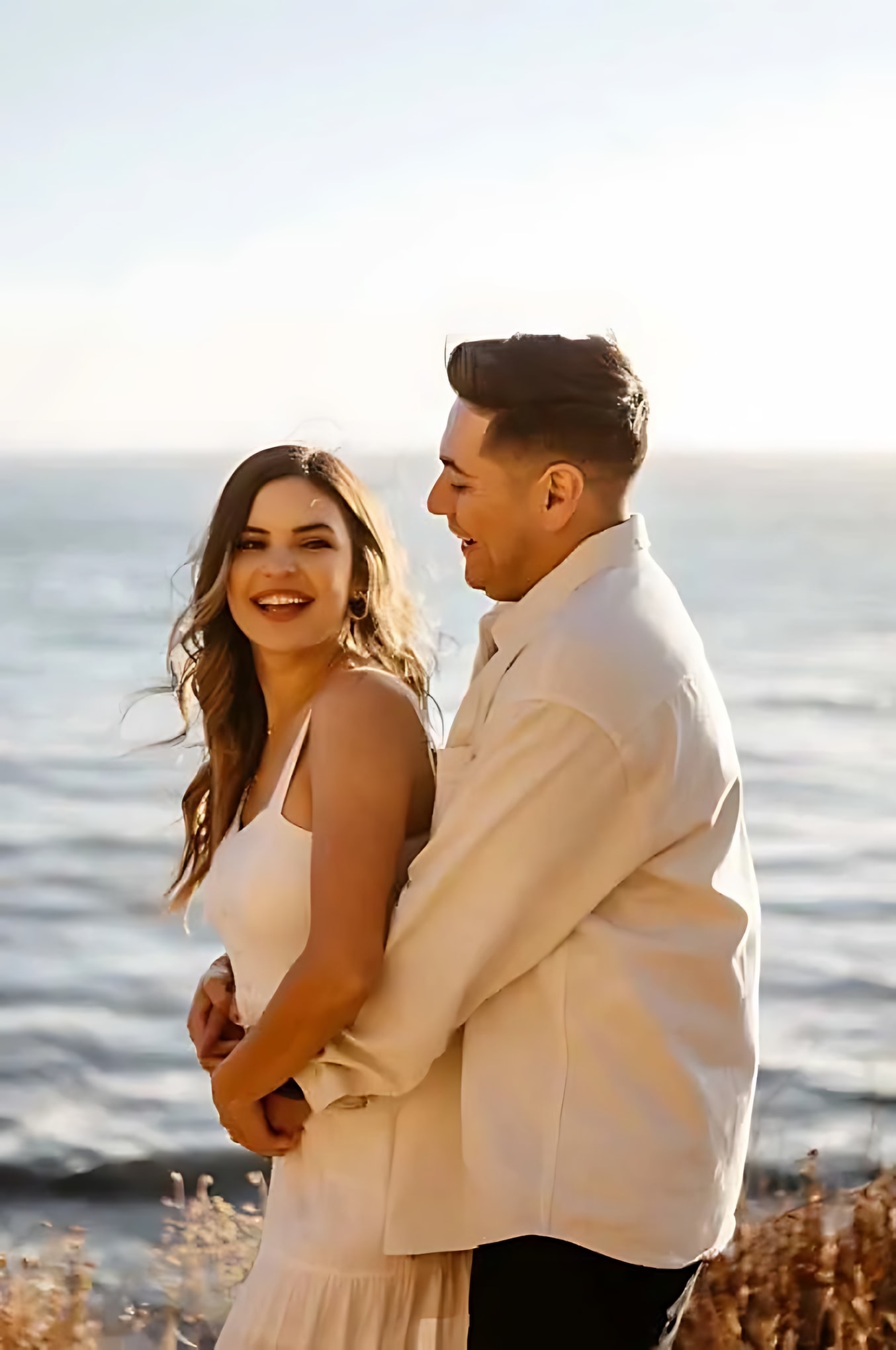Smiling couple embracing beside the ocean photographed by a wedding photographer in the Bay Area