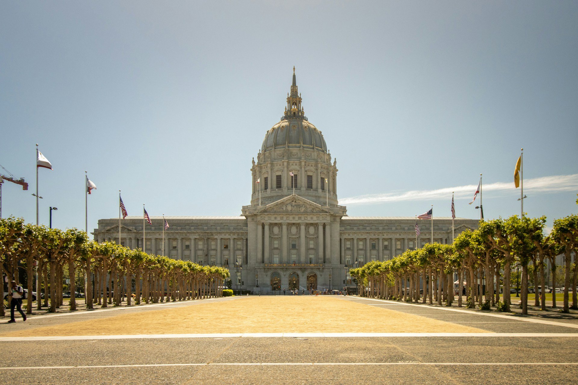 San Francisco City Hall seen head-on across its tree-lined plaza, the gilded dome bright against a clear sky