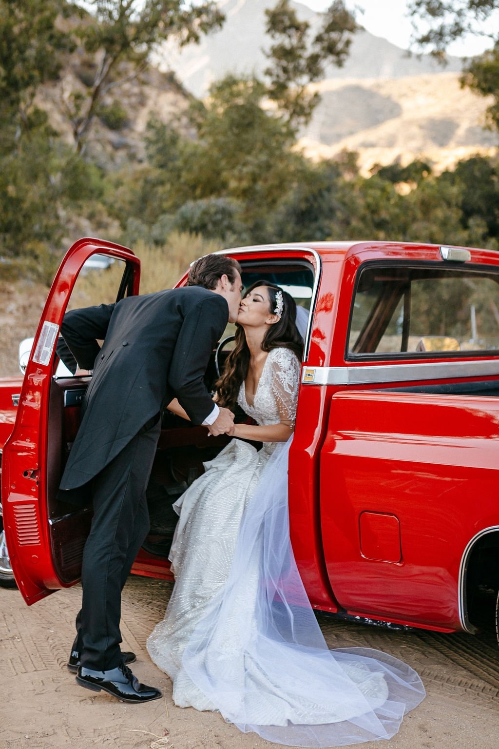 Bride and groom sharing a kiss beside a vintage red truck, photographed by one of the best wedding photographers in San Francisco for creative and memorable wedding imagery.