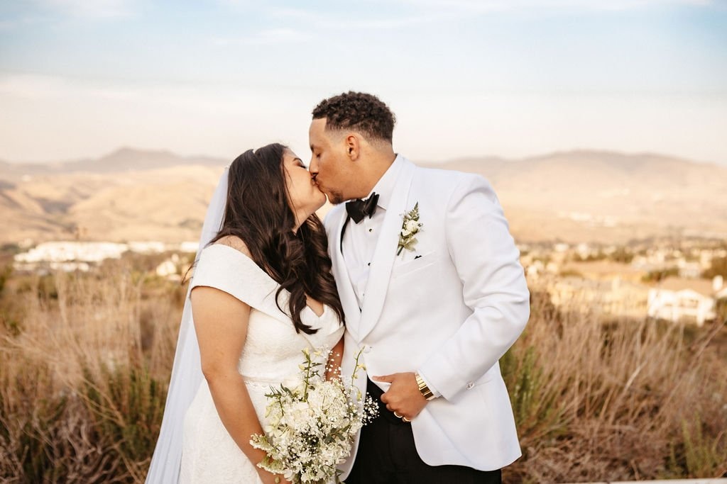 Bride and groom sharing a kiss during sunset portraits, showing how to choose a wedding photographer who captures natural and meaningful moments.