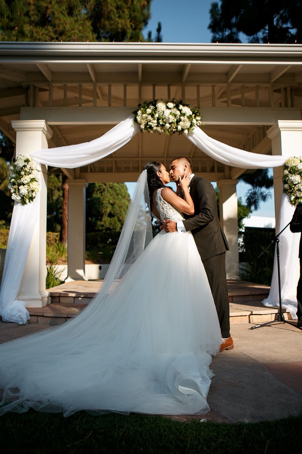 Bride and groom sharing a kiss beneath a decorated ceremony arbor, showing how to choose a wedding photographer who captures meaningful wedding moments.