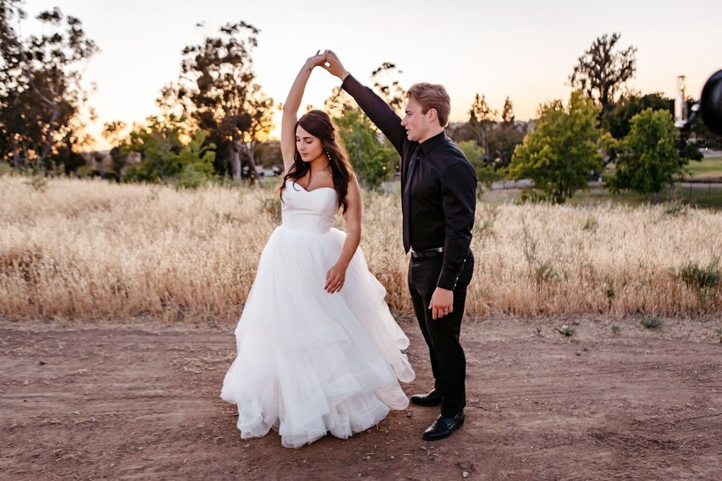 Couple twirling together during golden hour portraits, demonstrating how to select a wedding photographer who captures natural movement and genuine moments.