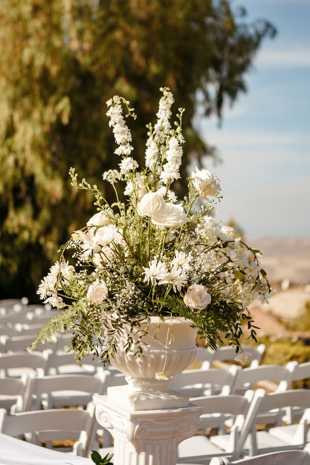A beautiful white flower arrangement is on display at an outdoor venue for a couple who knows what questions to ask your wedding photographer